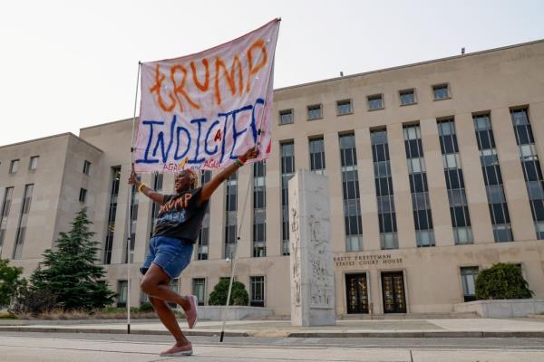 A protestor holds a banner in front of the federal courthouse after he was indicted again.  