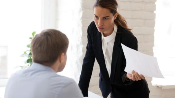 Serious businesswoman blaming employee for mistake in paper docu<em></em>ment