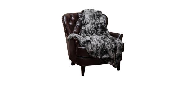 a gray faux fur throw blanket draped over a brown leather chair