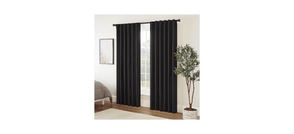 black floor-length curtains hung by a window