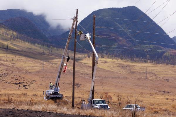 Electrical workers repair power lines leading into the fire ravaged town of Lahaina